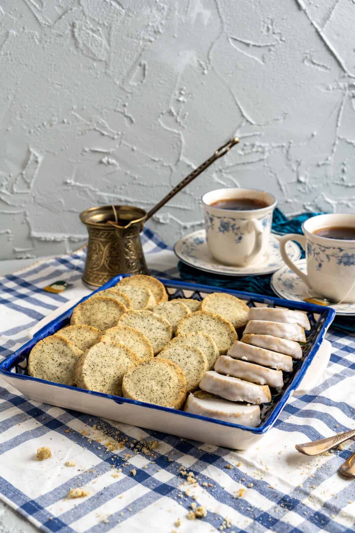 earl greyshortbread cookies with tea cups in the backdrop on blue and white tablecloth.