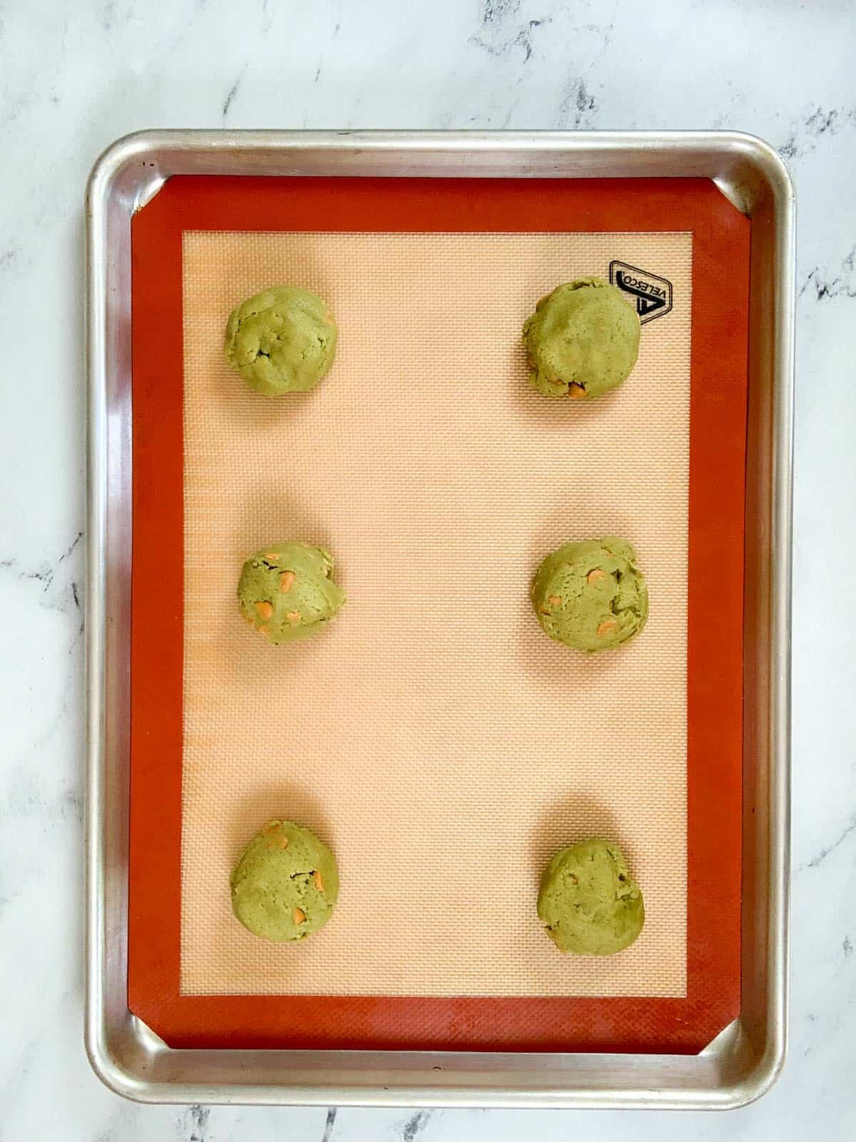 six matcha cookies on a baking tray ready to go in the oven to be baked. 