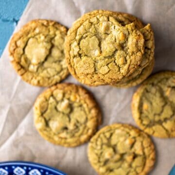 matcha cookies stacked on each other over brown paper.