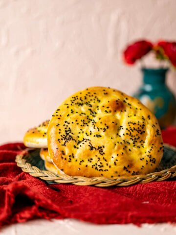 A whole turkish bread spread over a red table cloth.