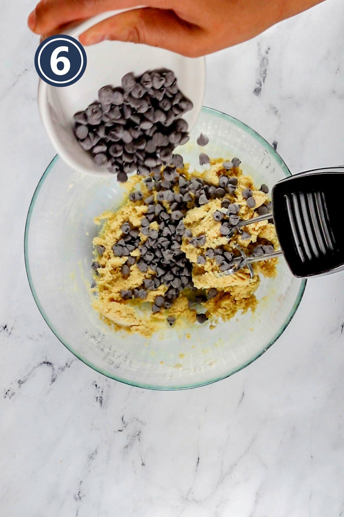 mixing the chocolate chips into the batter using an electric mixer.